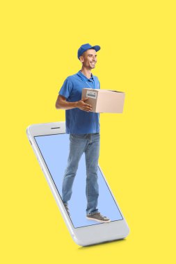 Sarı arka planda cep telefonu ve paketi olan erkek kurye.