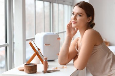 Kozmetik ürünleri için küçük buzdolabı olan güzel bir kadın.