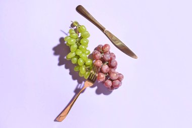 Hafif arka planda lezzetli üzümler ve çatal bıçak takımı