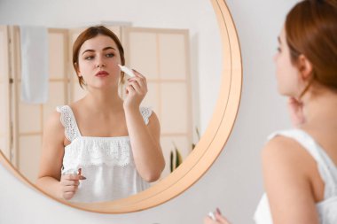 Güzel genç bir bayanın banyoda cildiyle ilgilendiği bir sabah.