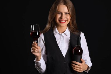 Siyah arka planda şarabı olan güzel bir kadın şarap garsonu.