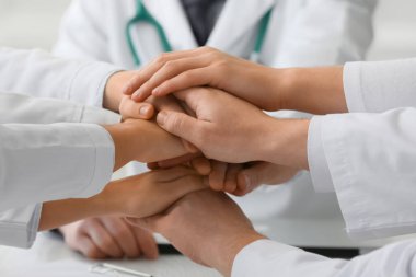 Klinikte el ele tutuşan bir grup doktor, yakın plan.