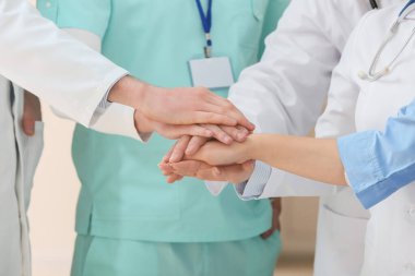 Klinikte el ele tutuşan bir grup doktor.