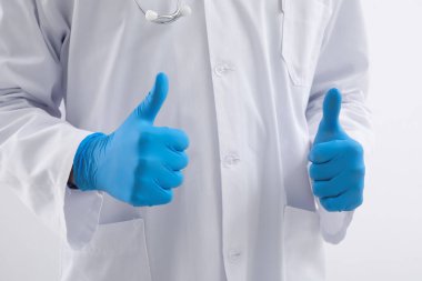 Lastik eldivenli erkek doktor arka planda baş parmak gösteriyor, yakın plan.