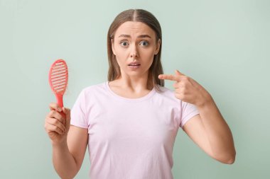 Stresli, saç dökülmesi sorunu olan ve yeşil arka planı olan genç bir kadın.