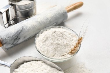 Beyaz arka planda buğday unu ve oklavalı kase, yakın plan.