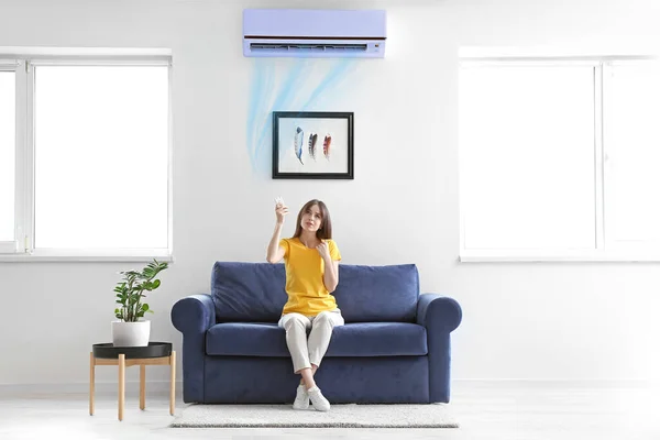 Jonge Vrouw Inschakelen Airconditioner Zittend Bank Thuis — Stockfoto