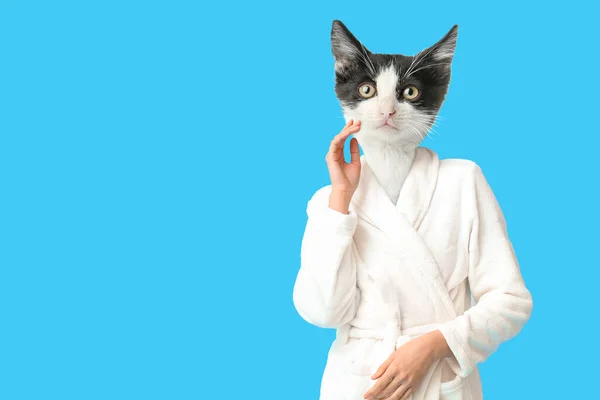 Cute cat with human body wearing bathrobe on light blue background