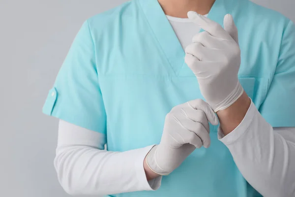 Mężczyzna Pielęgniarka Zakładanie Gumowe Rękawiczki Szarym Tle Zbliżenie — Zdjęcie stockowe