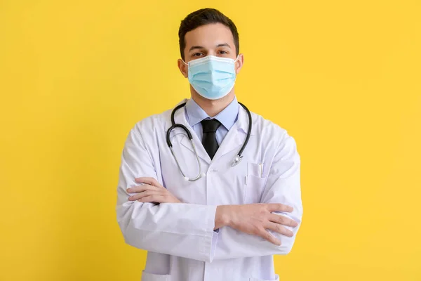 Male doctor in medical mask on yellow background