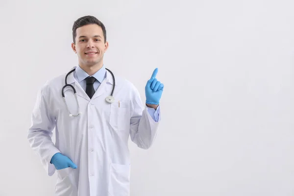 Mężczyzna Lekarz Gumowe Rękawiczki Wskazując Coś Lekkim Tle — Zdjęcie stockowe