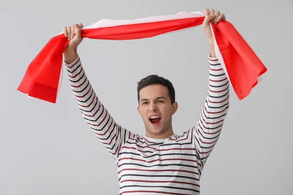 Screaming young man with flag of Poland on light background