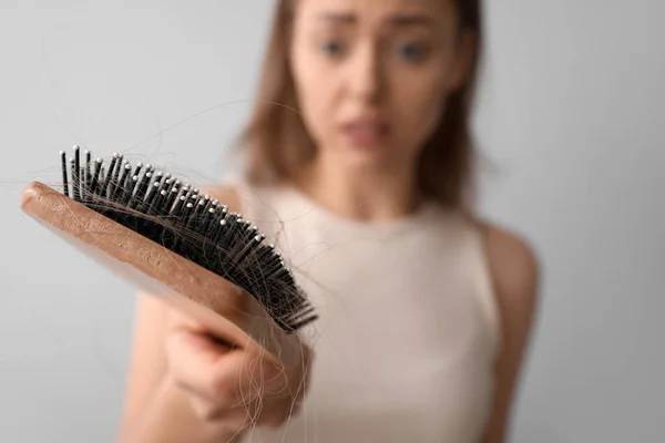 Молода Жінка Проблемою Випадіння Волосся Тримає Щітку Світлому Фоні Крупним — стокове фото