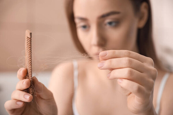 Young woman with hair loss problem  at home, closeup