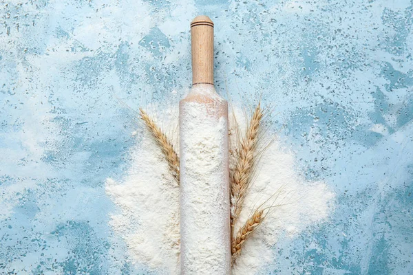 Arkaplanda un ve buğday kulaklı tahta oklavalar.