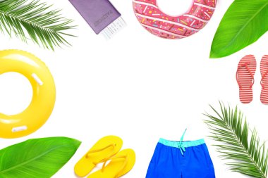 Beyaz arka planda plaj aksesuarları ve tropikal yapraklardan yapılmış çerçeve