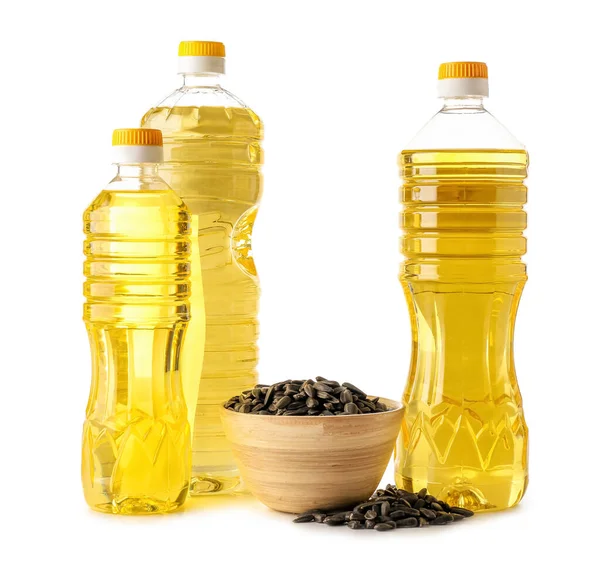 Beyaz zemin üzerinde ayçiçeği tohumları olan farklı yağ ve kase şişeleri.