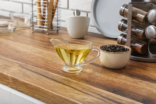 Gravy boat of oil and bowl with sunflower seeds on table in kitchen