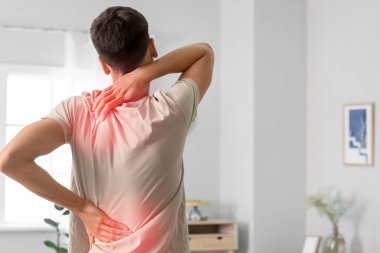 Evde omurgası ağrıyan genç bir adam.