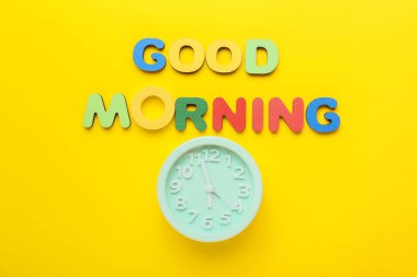 Renkli harflerden ve sarı arkaplandaki alarmlı saatten oluşan İyi Sabahlar metni