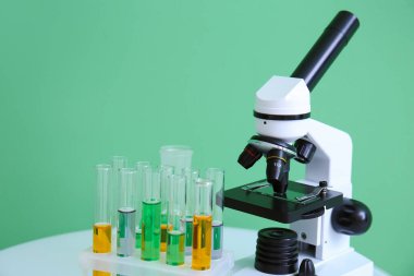 Yeşil arkaplanda örnekleri olan modern mikroskop ve test tüpleri