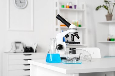 Tıp laboratuarında modern mikroskop ve kimyasal cam eşyalar.