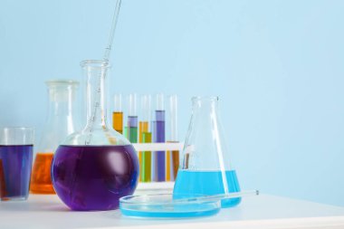 Mavi duvarın yanındaki masada farklı bir laboratuar cam parçası var.