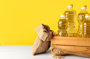 Sarı arka planda ayçiçeği tohumlarıyla dolu bir kutu dolusu yağ, torba ve kaşık.