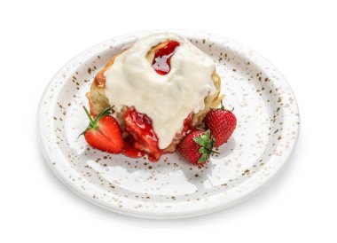 Beyaz arka planda çilekli tarçınlı rulo ve kremalı tabak