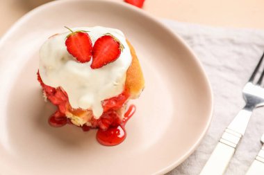 Bej arka planda çilekli tarçınlı ve kremalı tabak, yakın plan.