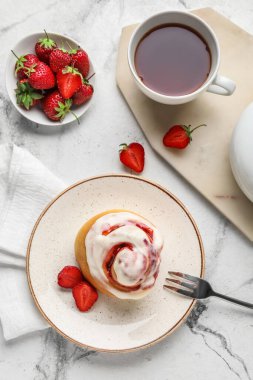 Çilekli tarçınlı tabak ve arka planda bir fincan çay.