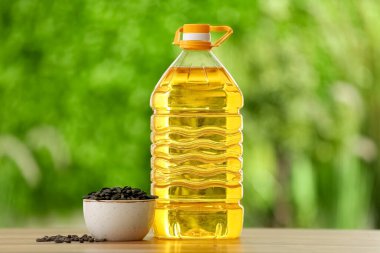 Bir şişe ayçiçeği yağı ve açık havada tohumlu kase.
