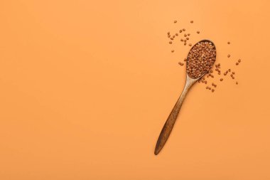 Arkaplanda karabuğday taneleri olan tahta kaşık.