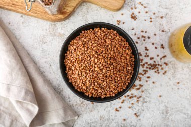 Açık arkaplanda karabuğday taneleri olan bir kase