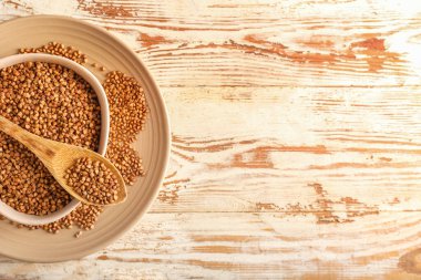 Tabaklar ve kaşık hafif ahşap zemin üzerinde karabuğday taneleri