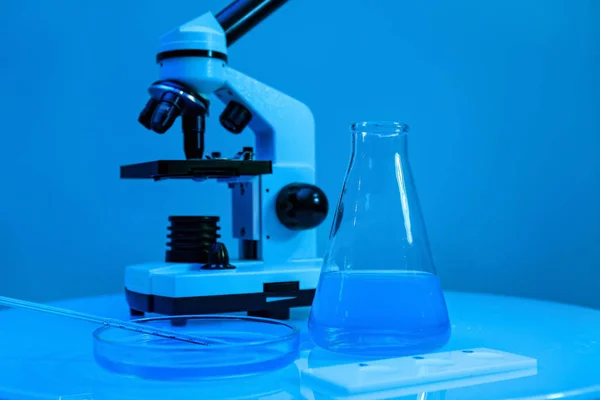 Różne Laboratoryjne Wyroby Szklane Próbkami Mikroskopem Stole Pobliżu Niebieskiej Ściany — Zdjęcie stockowe