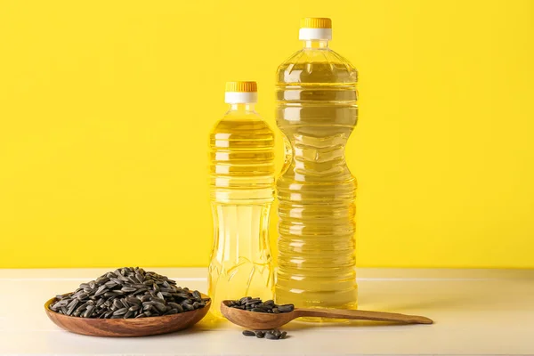 Bottles Oil Bowl Spoon Sunflower Seeds Table Yellow Background — Stock Photo, Image