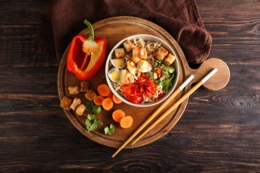 Tahta arka planda tavuk ve sebzeli bir kase lezzetli erişte.