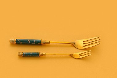 Sarı zemin üzerinde paslanmaz çelik çatallar