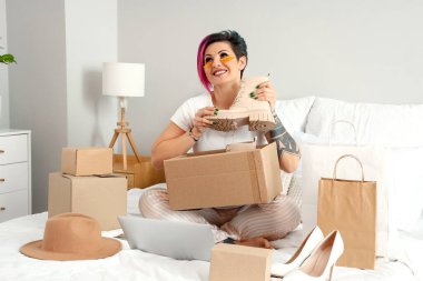 Yatak odasında yeni ayakkabıları olan güzel bir kadın. İnternetten alışveriş