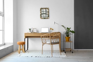 Işık duvarının yanında boş çerçeve ve dizüstü bilgisayarı olan modern işyeri