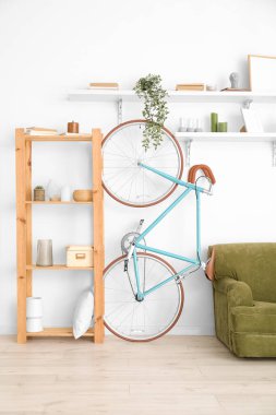 Şık dekorlu raflar ve oturma odasındaki beyaz duvarın yanında bisiklet.