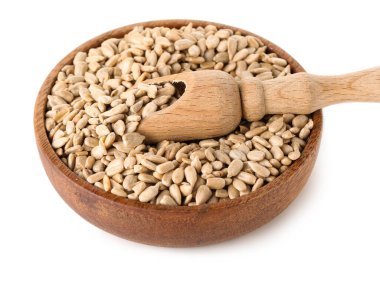 Ahşap kase ve kepçeyle kabuğu soyulmuş ayçiçeği tohumları beyaz arka planda, yakın plan