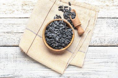 Kase, kepçe ve peçeteyle beyaz ahşap arka planda ayçiçeği tohumları