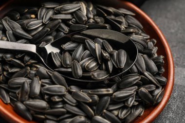 Kaşık ve siyah ayçiçeği tohumlu kase koyu arkaplanda, yakın plan