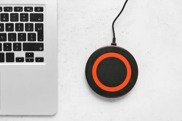 Wireless charger pad and laptop on light background