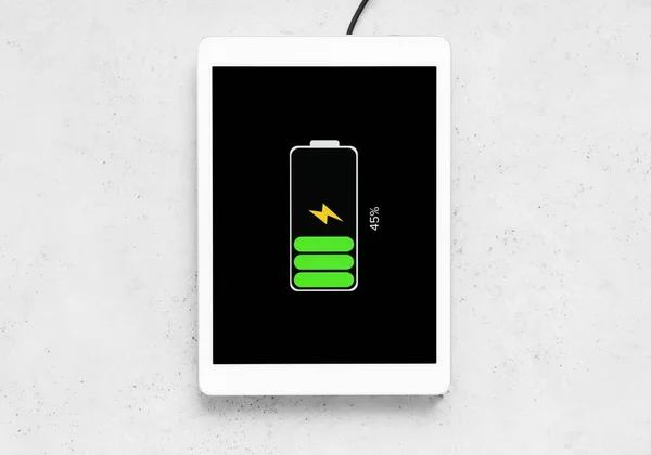 Tablet computer charging with wireless pad on grunge background