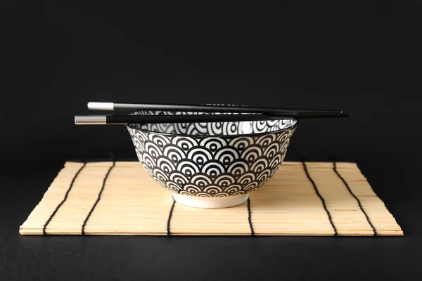 Chinese bowl with chopsticks on dark background