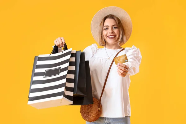 若いです女性でショッピングバッグやクレジットカードで黄色の背景 — ストック写真