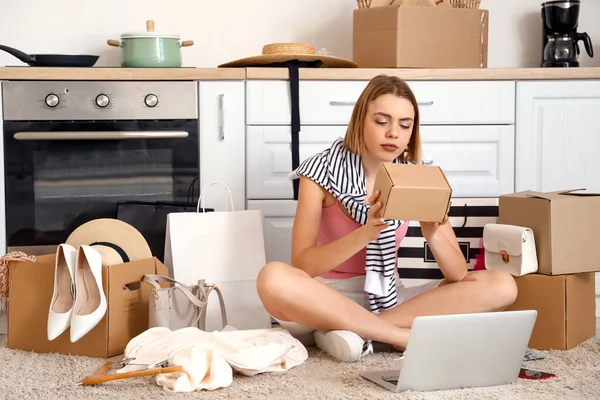 Young woman with parcel in kitchen. Online shopping